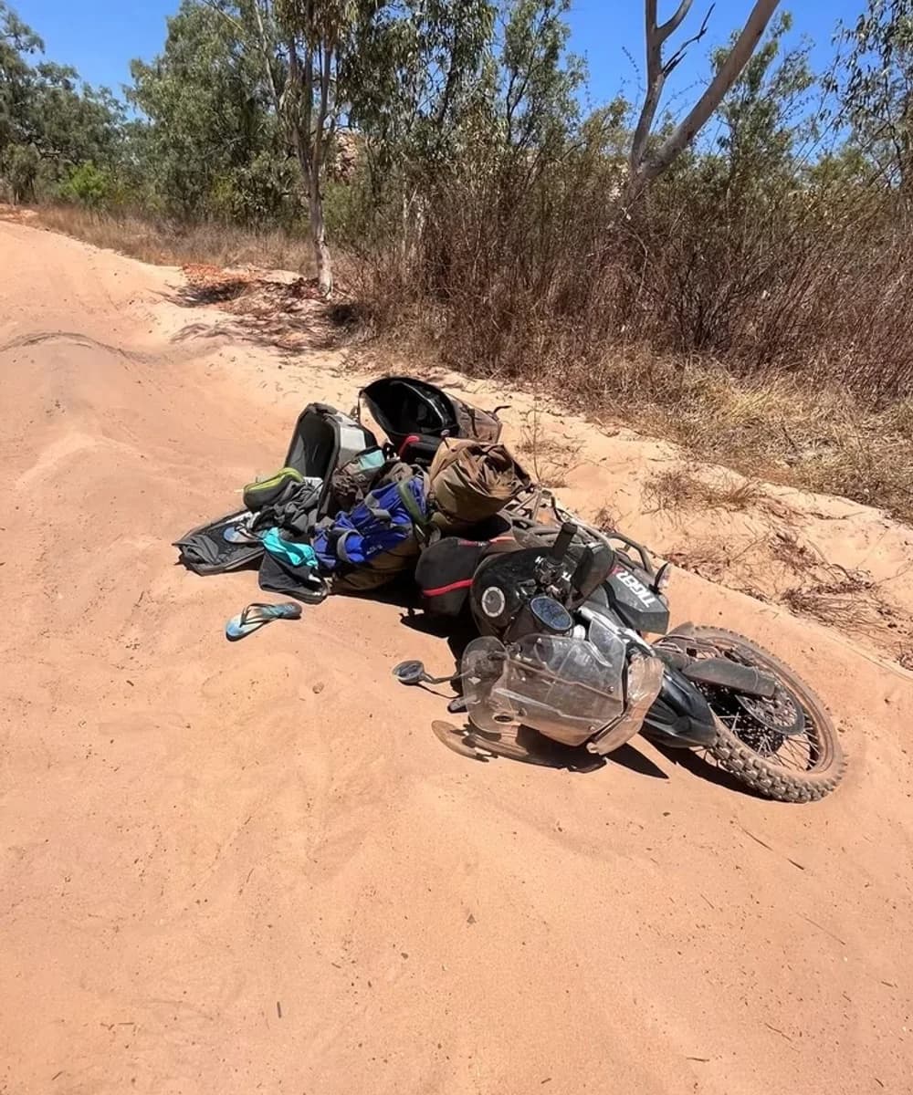 Loaded expedition motorcycle on its side after a crash on a remote dirt road